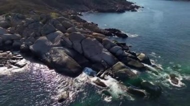 Bulgaristan 'ın parlak güneşli akşam günbatımına karşı sakin, mavi yansıtıcı Karadeniz ve eski karanlık kayalık taşlarla kaplı deniz manzarası. UHD 4K video gerçek zamanlı