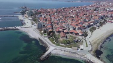 Bulgaristan 'ın kayalık yarımadasında bulunan ve büyük mavi, tuzlu Karadeniz tarafından turlanan küçük ve yoğun nüfuslu Pomorie kasabasına kuş bakışı bir bakış. UHD 4K video gerçek zamanlı