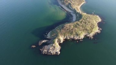 Bulgaristan 'ın parlak güneşli akşam günbatımına karşı sakin, mavi yansıtıcı Karadeniz ve eski karanlık kayalık taşlarla kaplı deniz manzarası. UHD 4K video gerçek zamanlı