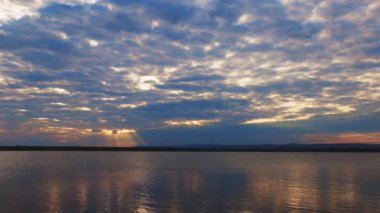 Boundless calm Black Sea with cool water reflecting light extends beyond the horizon, under colored sky with white volatile clouds and a bright dawn warm spring sun. UHD 4K video slow-motion
