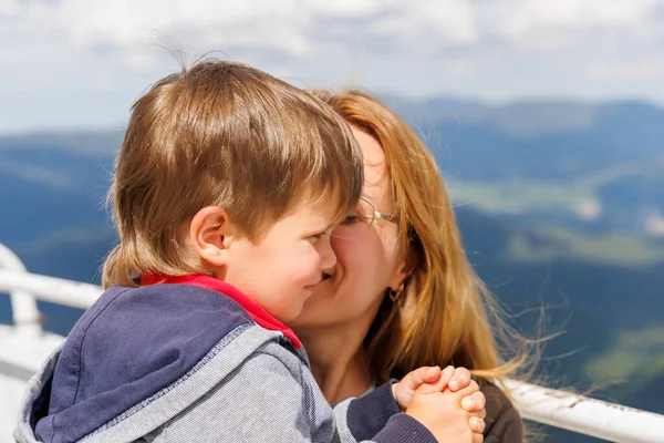 Annesini önemseyen küçük oğlunu Snezhan 'ın tepesindeki yüksek gözlem kulesinde Rodop Dağları' nın dağ ormanı vadisinin zemininde ve açık mavi bulutlu gökyüzünde sever.