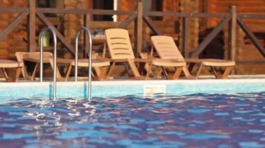 Sıcak, parlak bir günbatımının arka planına karşı yaz tatilinde, şeffaf, küçük ışık dalgaları ile serin, derin bir havuzun üst görüntüsü. 4K UHD yavaş çekim videosu