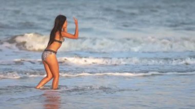 Siyah saçlı, şişman, dalgın ve esmer bir kız. Mavi sığ denizde yürüyor. Küçük dalgalarla ve ılık yaz güneşinin tadını çıkarıyor.