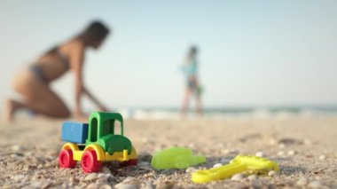 Birçok parlak renkli plastik oyuncaklar sıcak yaz güneşinin altında mavi fırtınalı denizin yakınındaki büyük bir kumlu sahilde uzanır.