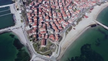 Küçük, yeni inşa edilmiş bir tatil köyünün kuş bakışı manzarası - Pomorie yarımadası, büyük, tuzlu, sakin Karadeniz 'de birçok farklı modern tekne ve tekne. UHD 4K video gerçek zamanlı