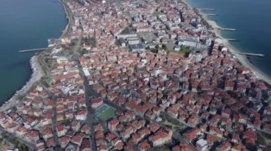Bulgaristan 'ın kayalık yarımadasında bulunan ve büyük mavi, tuzlu Karadeniz tarafından turlanan küçük ve yoğun nüfuslu Pomorie kasabasına kuş bakışı bir bakış. UHD 4K video gerçek zamanlı