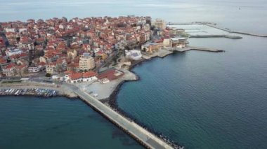 Küçük, yeni inşa edilmiş bir tatil köyünün kuş bakışı manzarası - Pomorie yarımadası, büyük, tuzlu, sakin Karadeniz 'de birçok farklı modern tekne ve tekne. UHD 4K video gerçek zamanlı