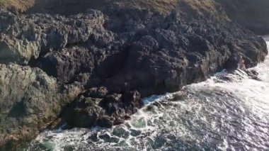 Bulgaristan 'ın parlak güneşli akşam günbatımına karşı sakin, mavi yansıtıcı Karadeniz ve eski karanlık kayalık taşlarla kaplı deniz manzarası. UHD 4K video gerçek zamanlı