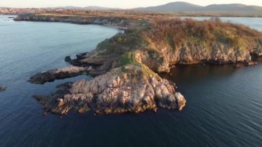 Bulgaristan 'ın açık mavi gökyüzü altında, sessiz turkuaz şeffaf Karadeniz ile çevrili, yabani çimenler ve otellerle kaplı kayalık kumlu dar sahillerin yükseklik ve yanından manzaraya bak. UHD 4K video gerçek zamanlı