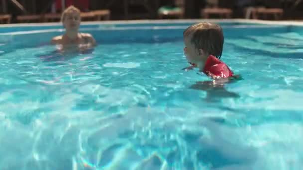 Little Cheerful Boy Bright Inflatable Armbands Swims Shallow Blue Pool — Stockvideo