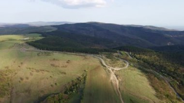 Birds eye view of spring blooming green meadows and wooded hilly slopes of the Balkan Mountains, under the light of a bright cloudy warm day in the country of Bulgaria. UHD 4K video realtime