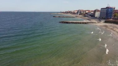 Bulgaristan 'ın kayalık yarımadasında bulunan ve büyük mavi, tuzlu Karadeniz tarafından turlanan küçük ve yoğun nüfuslu Pomorie kasabasına kuş bakışı bir bakış. UHD 4K video gerçek zamanlı