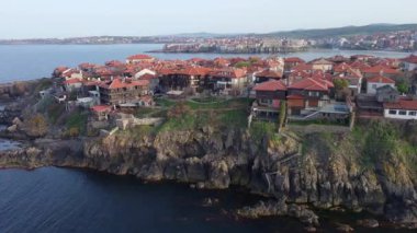 Birds eye view of the modern historic small town of Sozopol with a variety of cozy seaside houses and small sea spring boats, near the calm deep rippled Black Sea. UHD 4K video realtime