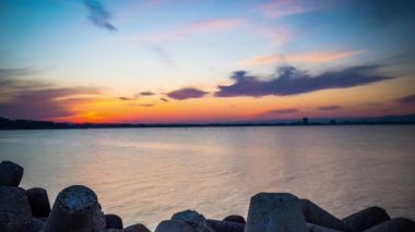 A small concrete reliable breakwater against the background of a spacious blue cloudy sky and a raging blue empty Black Sea, with white sea strong waves. 4K UHD timelapse video