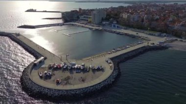 Küçük, yeni inşa edilmiş bir tatil köyünün kuş bakışı manzarası - Pomorie yarımadası, büyük, tuzlu, sakin Karadeniz 'de birçok farklı modern tekne ve tekne. UHD 4K video gerçek zamanlı