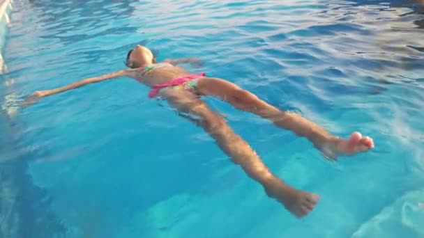 Маленькая Забавная Девочка Ярко Розовом Купальнике Плавает Спине Глубоком Голубом — стоковое видео