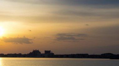 View of magical brilliant bewitching reflection in calm blue quiet Black Sea, against background of sea horizon with cloudy multi-colored sky and bright evening sunset. 4K UHD timelapse video