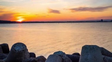 A small concrete reliable breakwater against the background of a spacious blue cloudy sky and a raging blue empty Black Sea, with white sea strong waves. 4K UHD timelapse video