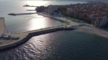 Küçük, yeni inşa edilmiş bir tatil köyünün kuş bakışı manzarası - Pomorie yarımadası, büyük, tuzlu, sakin Karadeniz 'de birçok farklı modern tekne ve tekne. UHD 4K video gerçek zamanlı