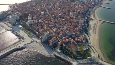 Küçük, yeni inşa edilmiş bir tatil köyünün kuş bakışı manzarası - Pomorie yarımadası, büyük, tuzlu, sakin Karadeniz 'de birçok farklı modern tekne ve tekne. UHD 4K video gerçek zamanlı