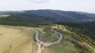 Birds eye view of spring blooming green meadows and wooded hilly slopes of the Balkan Mountains, under the light of a bright cloudy warm day in the country of Bulgaria. UHD 4K video realtime