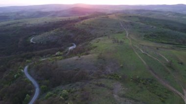 Birds eye view of spring blooming green meadows and wooded hilly slopes of the Balkan Mountains, under the light of a bright cloudy warm day in the country of Bulgaria. UHD 4K video realtime