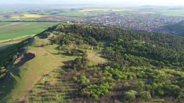 Birds eye view of spring blooming green meadows and wooded hilly slopes of the Balkan Mountains, under the light of a bright cloudy warm day in the country of Bulgaria. UHD 4K video realtime