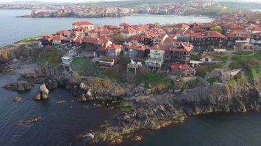 Birds eye view of the modern historic small town of Sozopol with a variety of cozy seaside houses and small sea spring boats, near the calm deep rippled Black Sea. UHD 4K video realtime