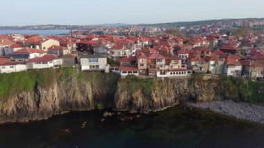 Birds eye view of the modern historic small town of Sozopol with a variety of cozy seaside houses and small sea spring boats, near the calm deep rippled Black Sea. UHD 4K video realtime