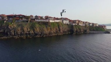 Birds eye view of the modern historic small town of Sozopol with a variety of cozy seaside houses and small sea spring boats, near the calm deep rippled Black Sea. UHD 4K video realtime