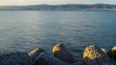 A small concrete reliable breakwater against the background of a spacious blue cloudy sky and a raging blue empty Black Sea, with white sea strong waves. 4K UHD timelapse video