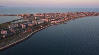 Bulgaristan 'ın kayalık yarımadasında bulunan ve büyük mavi, tuzlu Karadeniz tarafından turlanan küçük ve yoğun nüfuslu Pomorie kasabasına kuş bakışı bir bakış. UHD 4K video gerçek zamanlı