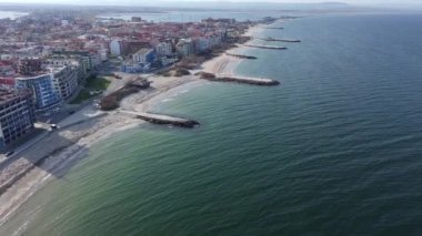 Bulgaristan 'ın kayalık yarımadasında bulunan ve büyük mavi, tuzlu Karadeniz tarafından turlanan küçük ve yoğun nüfuslu Pomorie kasabasına kuş bakışı bir bakış. UHD 4K video gerçek zamanlı