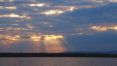 Boundless calm Black Sea with cool water reflecting light extends beyond the horizon, under colored sky with white volatile clouds and a bright dawn warm spring sun. UHD 4K video slow-motion