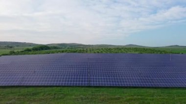 Modern eco-friendly large solar panels to generate energy from suns rays are installed in endless meadows with green grass, under a clear blue sky with bright warm spring sun. UHD 4K video realtime