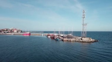 A small sea fishing port with boats in the calm deep cool Black Sea adjoins the ancient resort small town of Pomorie in Bulgaria, under a blue cloudy sky. UHD 4K video realtime