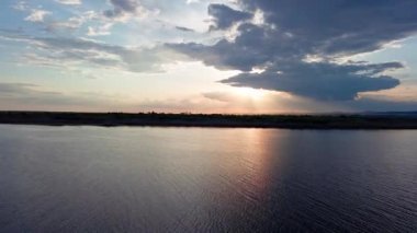 Boundless calm Black Sea with cool water reflecting light extends beyond the horizon, under colored sky with white volatile clouds and a bright dawn warm spring sun. UHD 4K video realtime