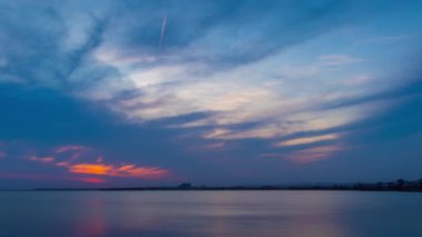 View of magical brilliant bewitching reflection in calm blue quiet Black Sea, against background of sea horizon with cloudy multi-colored sky and bright evening sunset. 4K UHD timelapse video