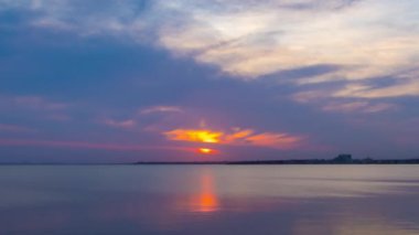 View of magical brilliant bewitching reflection in calm blue quiet Black Sea, against background of sea horizon with cloudy multi-colored sky and bright evening sunset. 4K UHD timelapse video