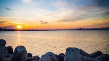 A small concrete reliable breakwater against the background of a spacious blue cloudy sky and a raging blue empty Black Sea, with white sea strong waves. 4K UHD timelapse video