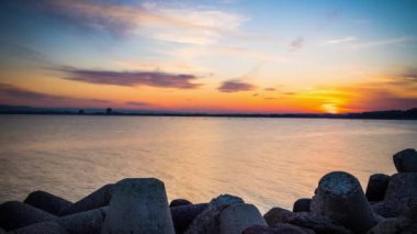 A small concrete reliable breakwater against the background of a spacious blue cloudy sky and a raging blue empty Black Sea, with white sea strong waves. 4K UHD timelapse video
