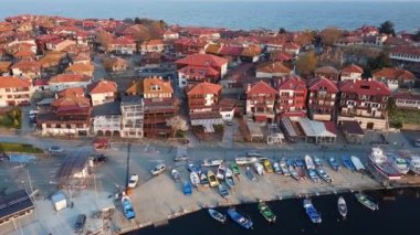 Küçük, yeni inşa edilmiş bir tatil köyünün kuş bakışı manzarası - Pomorie yarımadası, büyük, tuzlu, sakin Karadeniz 'de birçok farklı modern tekne ve tekne. UHD 4K video gerçek zamanlı