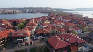 Birds eye view of the modern historic small town of Sozopol with a variety of cozy seaside houses and small sea spring boats, near the calm deep rippled Black Sea. UHD 4K video realtime
