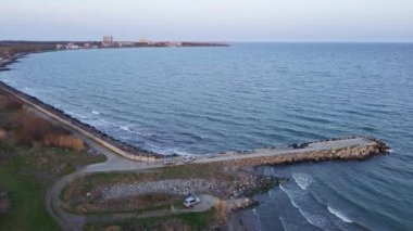 Birds eye view of dense spring green meadows and fields near rocky sandy steep coast, near calm rippled deep Black Sea in light of evening sea sun in warm country of Bulgaria. UHD 4K video realtime