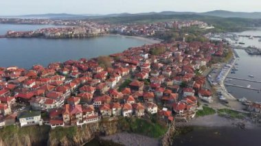 Birds eye view of the modern historic small town of Sozopol with a variety of cozy seaside houses and small sea spring boats, near the calm deep rippled Black Sea. UHD 4K video realtime