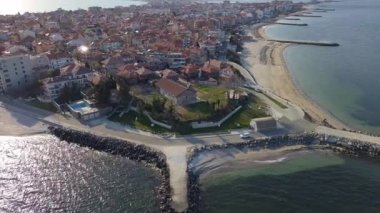 Bulgaristan 'ın kayalık yarımadasında bulunan ve büyük mavi, tuzlu Karadeniz tarafından turlanan küçük ve yoğun nüfuslu Pomorie kasabasına kuş bakışı bir bakış. UHD 4K video gerçek zamanlı
