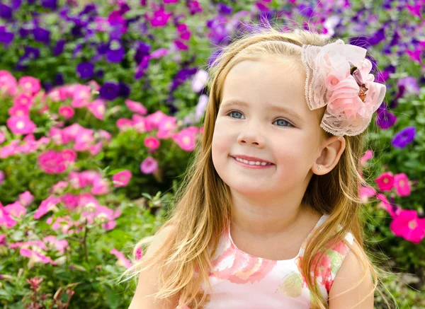Utomhus porträtt av söta lilla flicka nära blommorna — Stockfoto