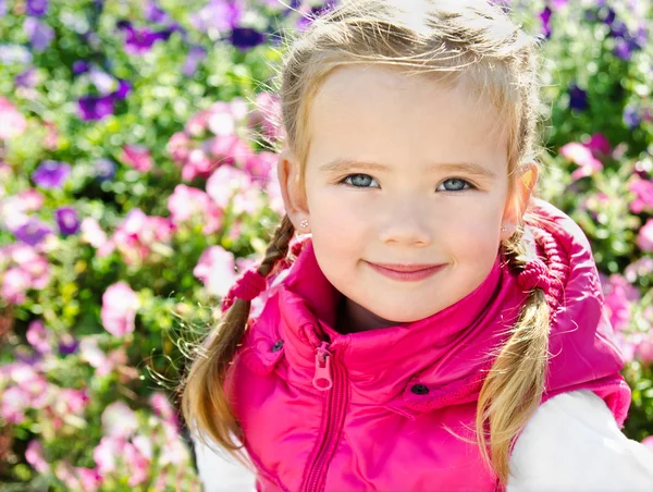 Outdoor portrait of cute little girl near the flowers — Stock Photo, Image