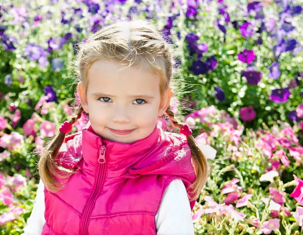 Outdoor portrait of cute little girl near the flowers — Stock Photo, Image