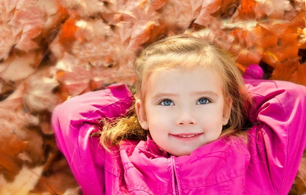 Yapraklarda yalan sevimli küçük kız portresi — Stok fotoğraf
